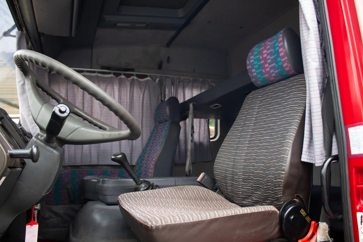 Interior de la cabina del Mercedes-Benz 814 rojo, con cucheta y cortinas