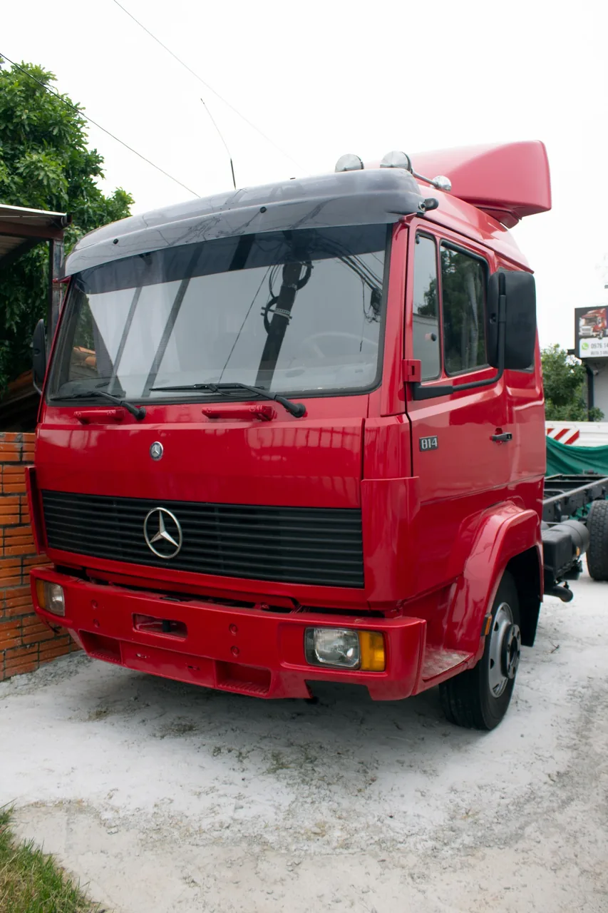 Mercedes-Benz 814 rojo sobre chasis sin carrocería, de frente en el patio