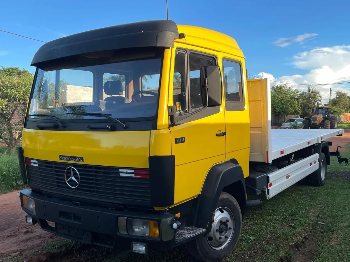 Mercedes-Benz 1117 doble cabina amarilla con plancha, de frente en el patio